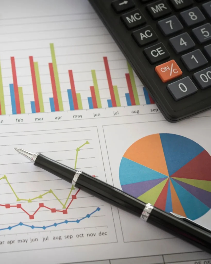Financial sheet with bar and pie charts, with black calculator and pen on it