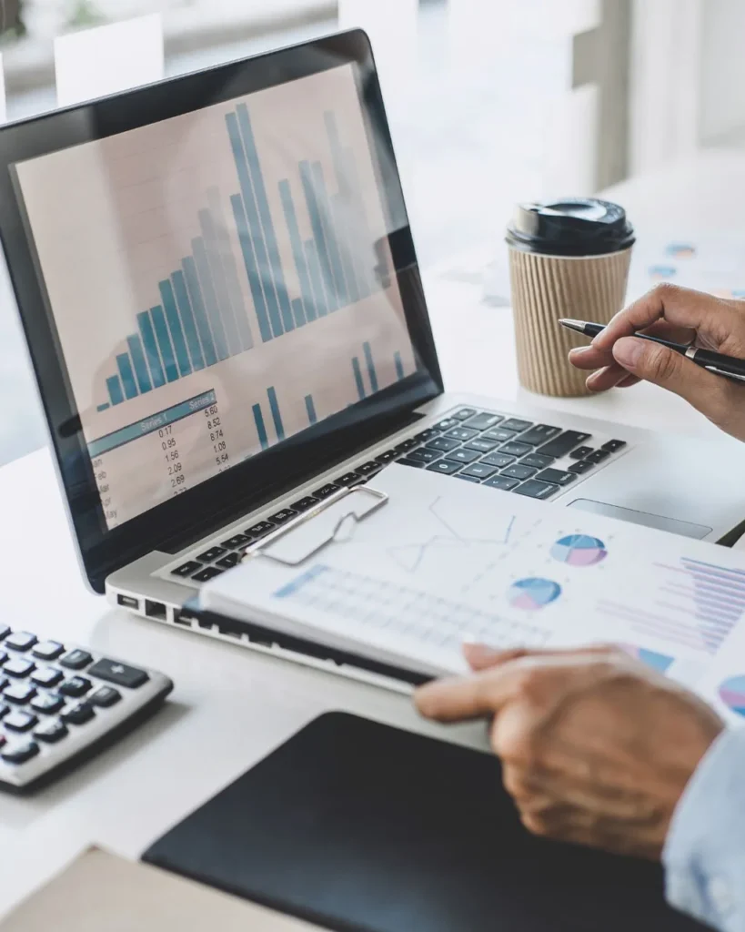 A businessman focused on his laptop, analyzing financial data with charts and graphs displayed on the screen.