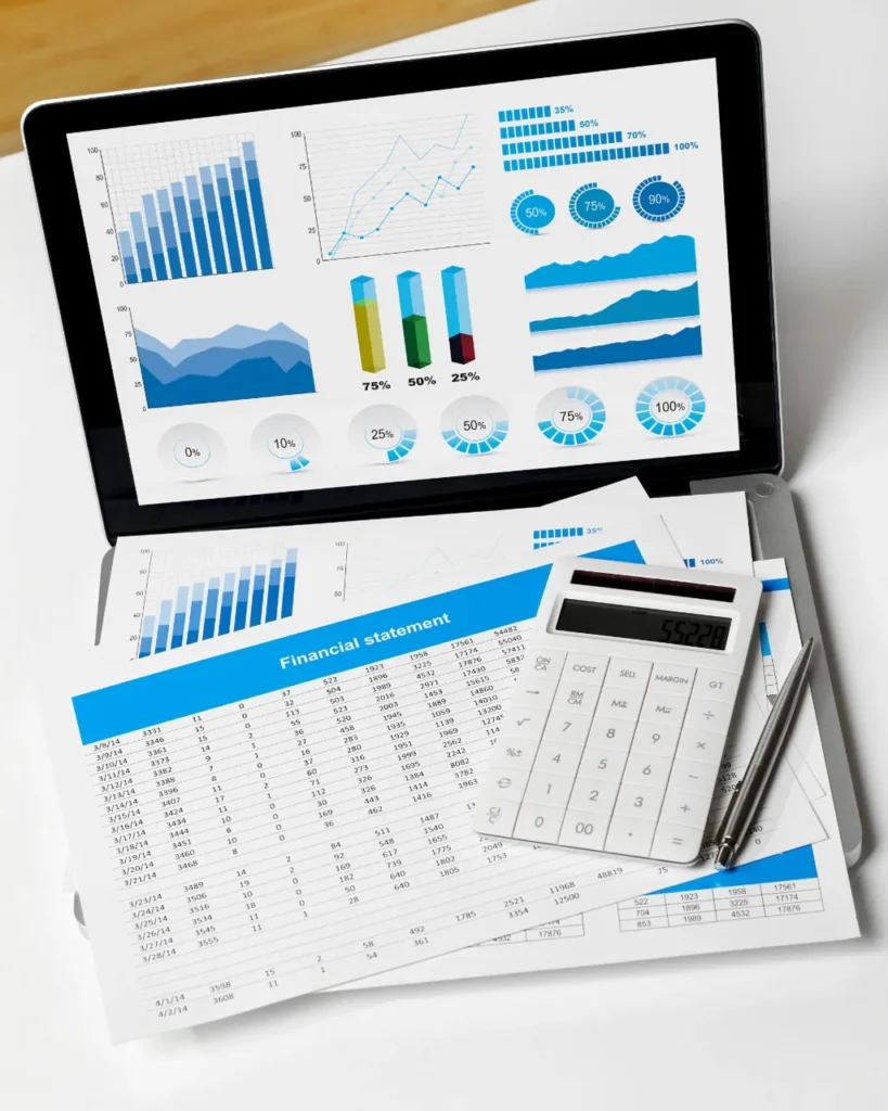 A desk featuring a laptop and calculator, with financial data and sheets