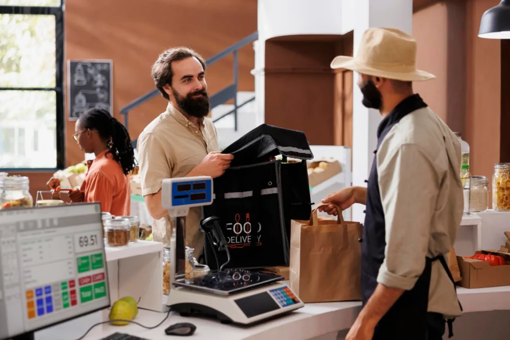 Restaurant cashier using a POS terminal to complete a transaction for a customer with a pickup order.