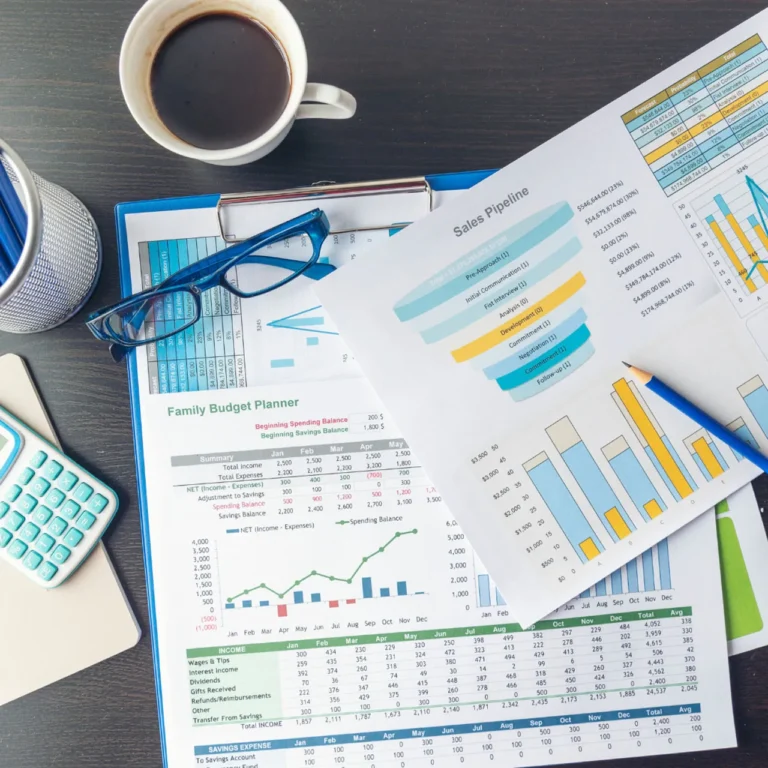 A desk featuring a laptop and calculator, with financial data and sheets